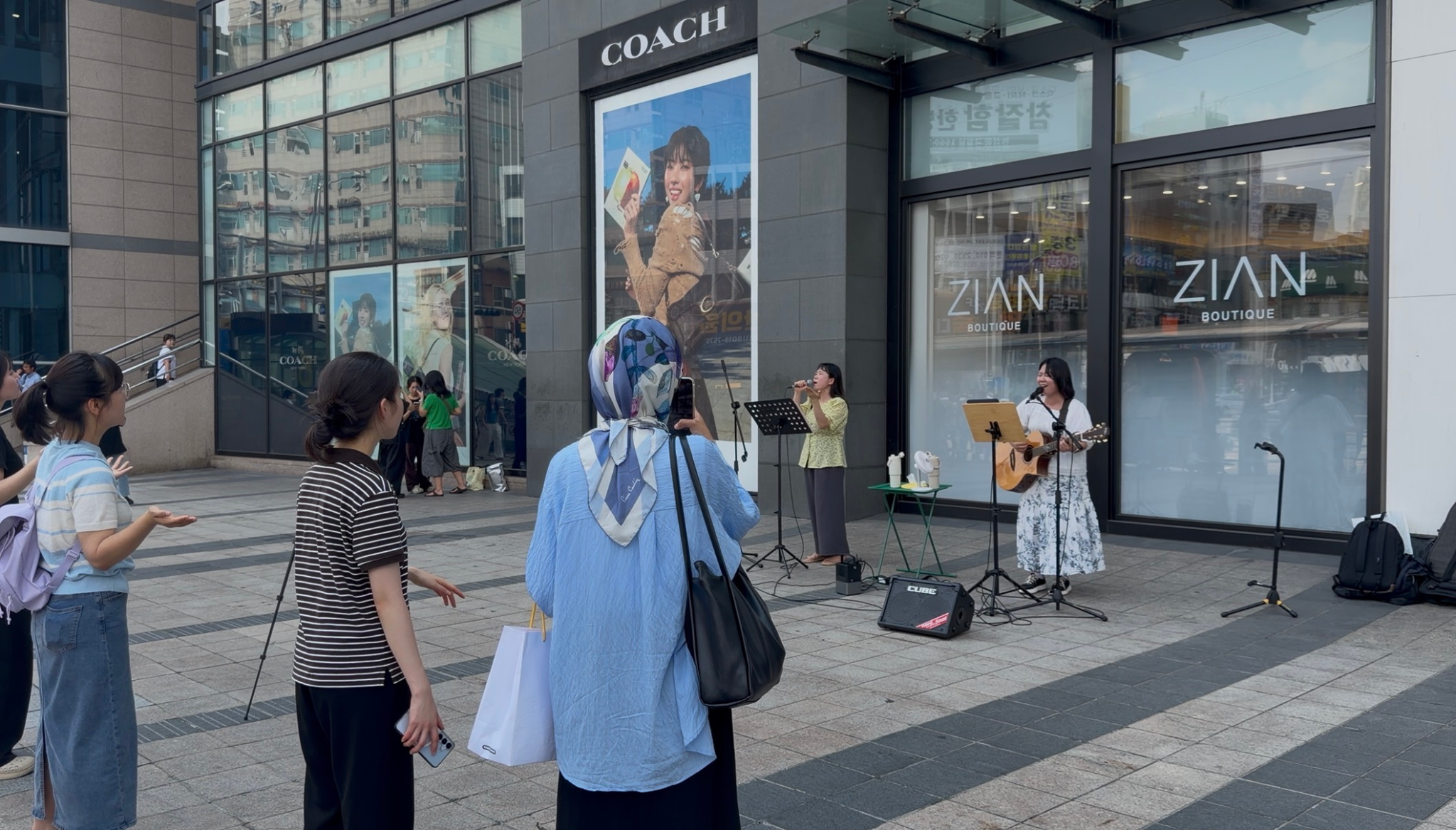 노래와 기타 연주가 진행되는 버스킹을 바라보는 사람들