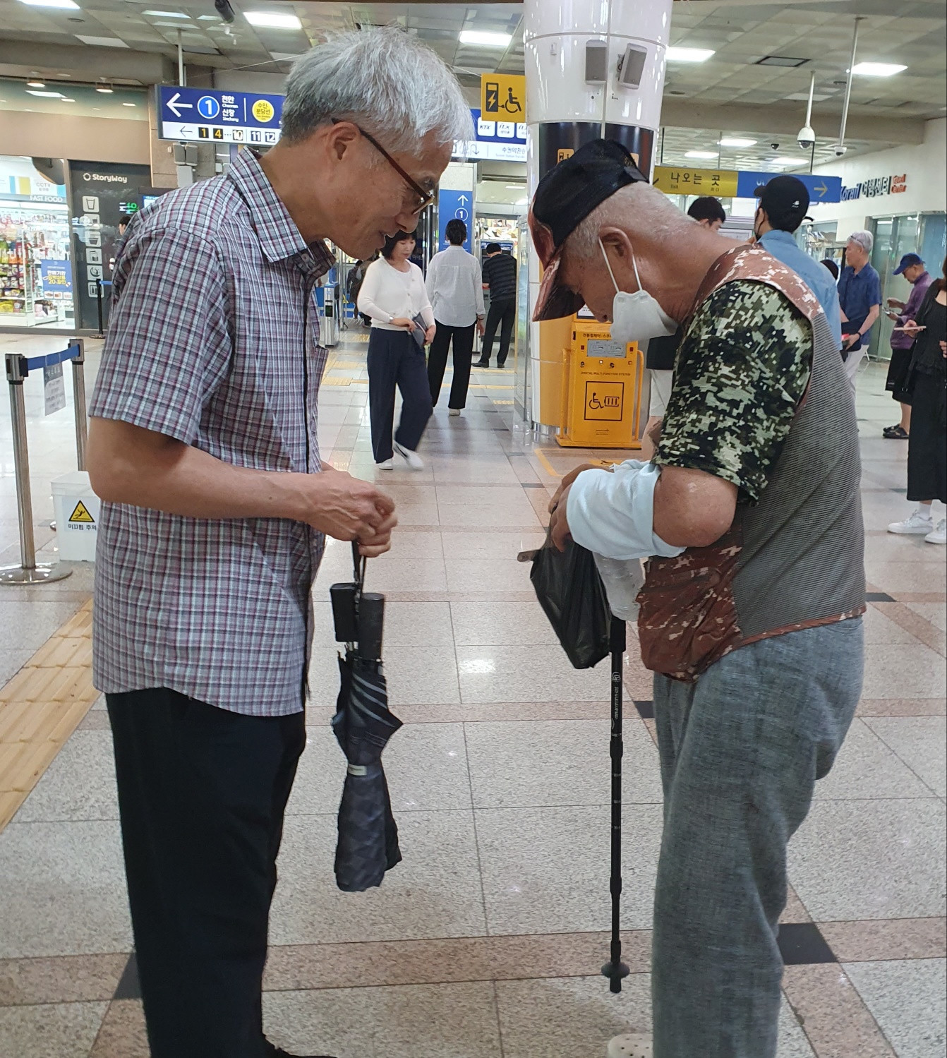 역 내부에서 두 성인이 마주 서서 대화하는 모습