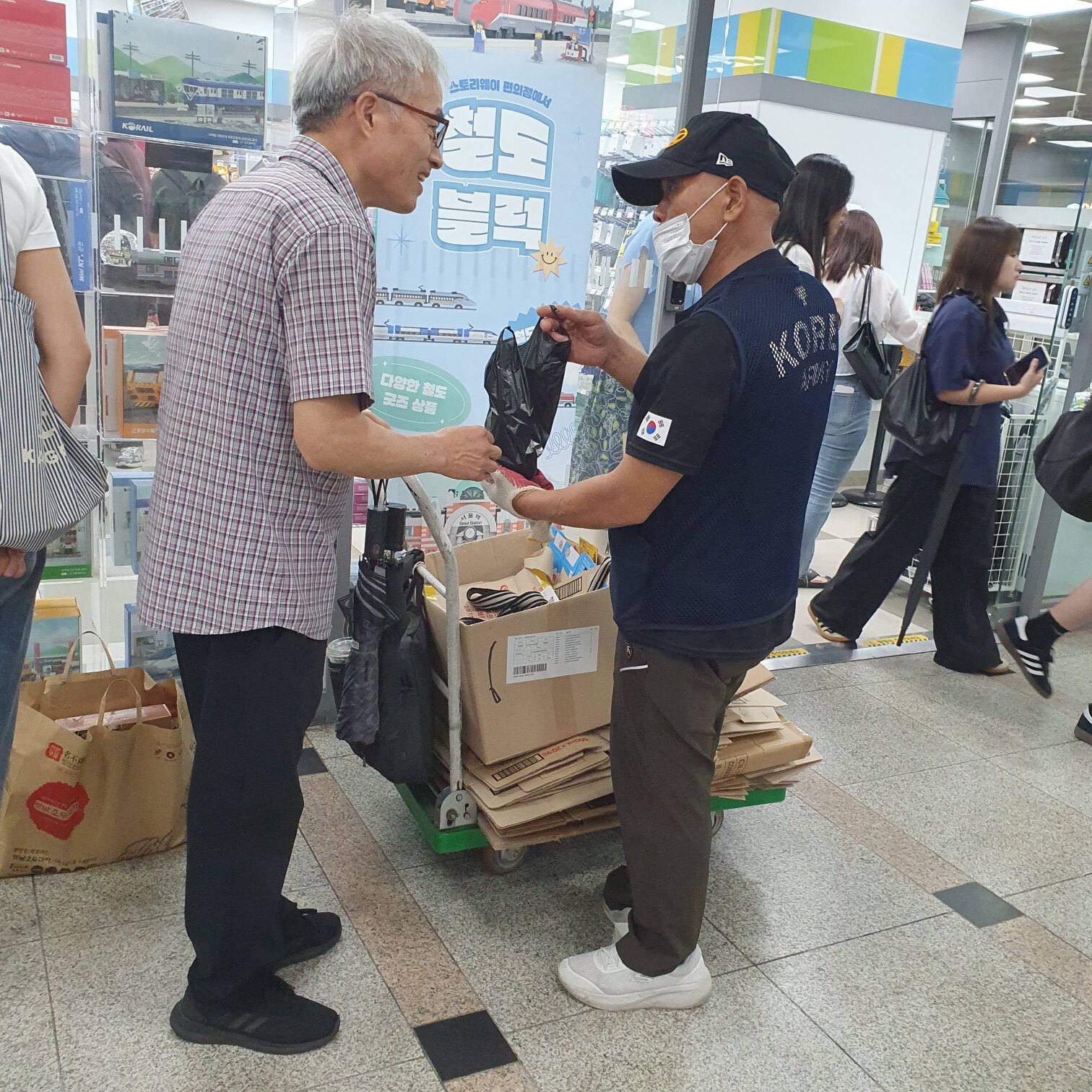 역 안에서 봉투를 건네며 대화하는 모습