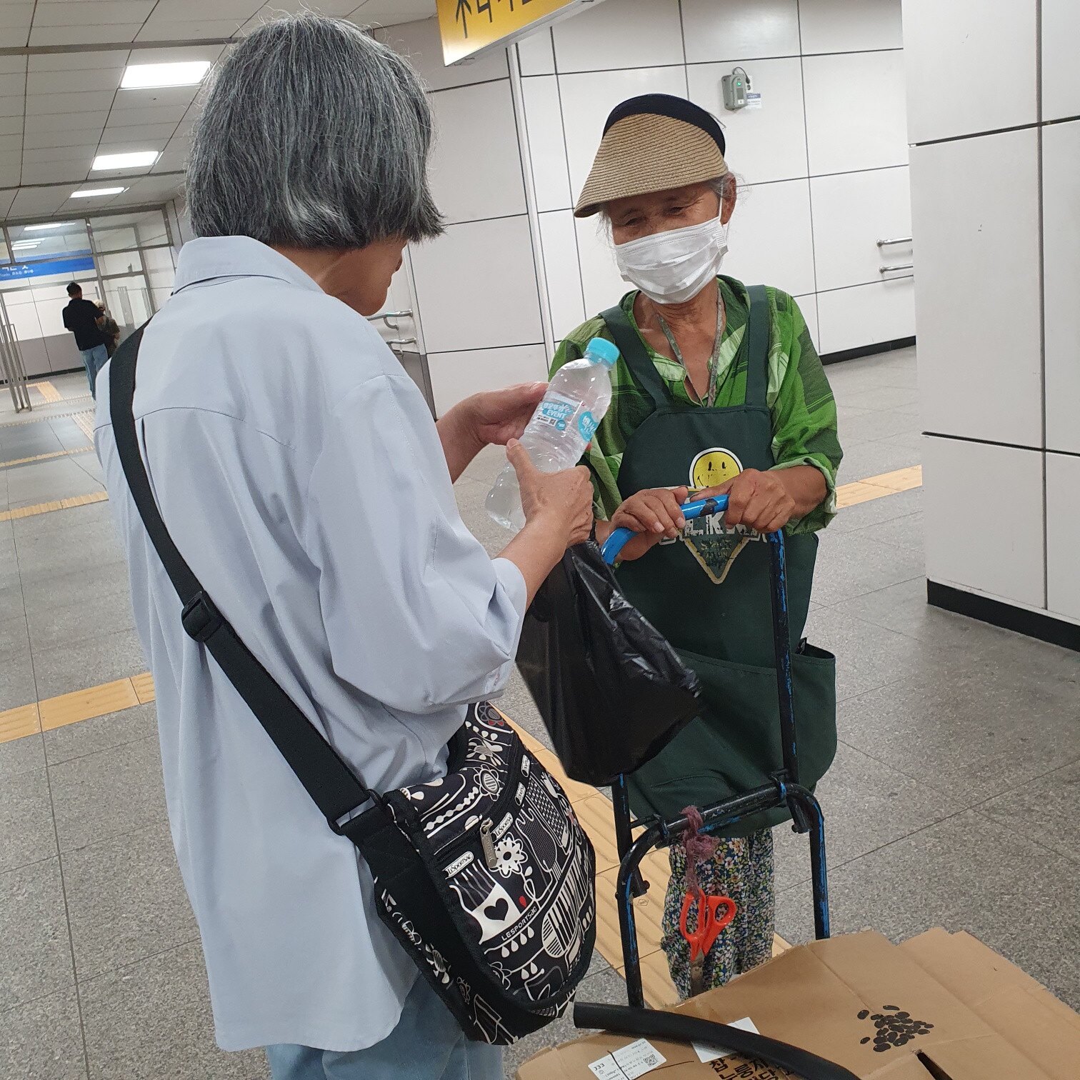 역 안에서 물병을 건네며 이야기를 나누는 모습
