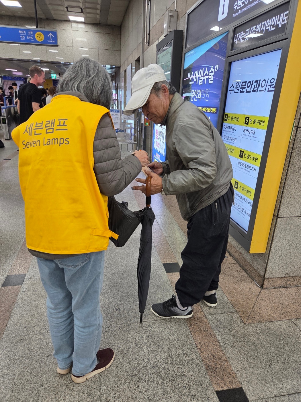 역 안내판 곁에서 물품을 나누는 모습